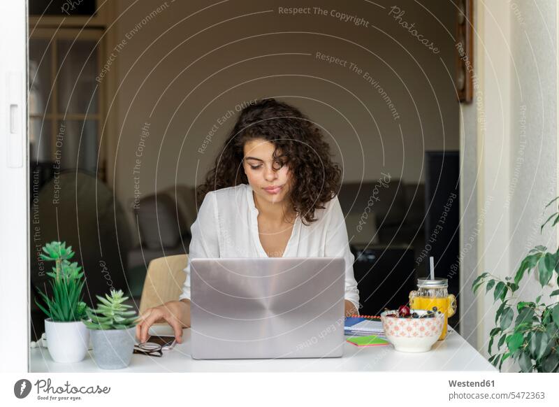 Young woman using cell phone and laptop at desk human human being human beings humans person persons caucasian appearance caucasian ethnicity european 1