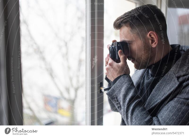 Young man taking pictures at the window human human being human beings humans person persons secret agent secret agents spies Occupation Work job jobs