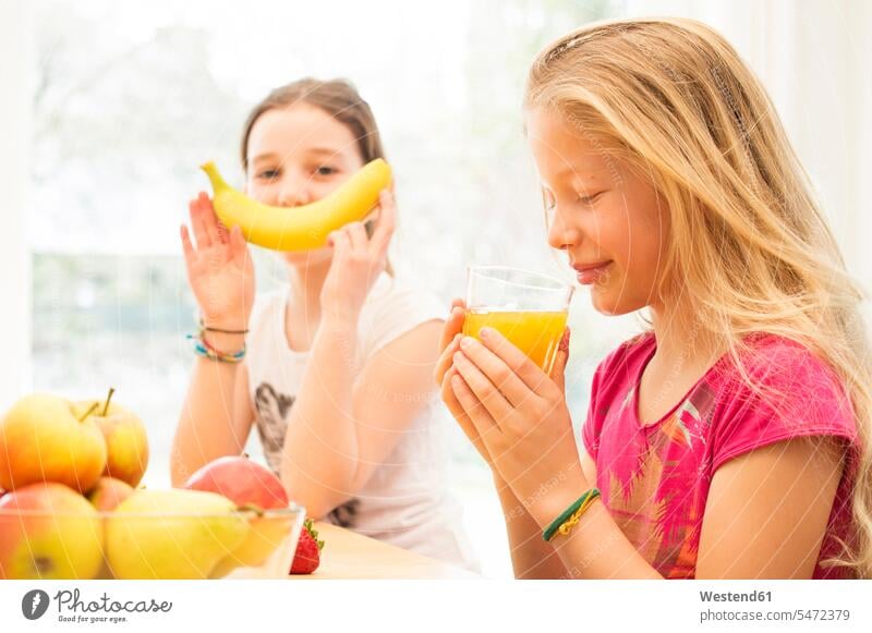Portrait of girl drinking glass of orange juice while her friend having fun with banana Orange Oranges Banana Bananas Orange Juice Fun funny girlfriend