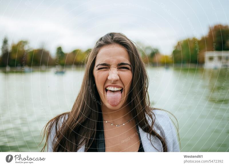 Portrait of woman at a lake sticking out her tongue touristic tourists delight enjoyment Pleasant pleasure Cheekiness impertinence impertinent free time