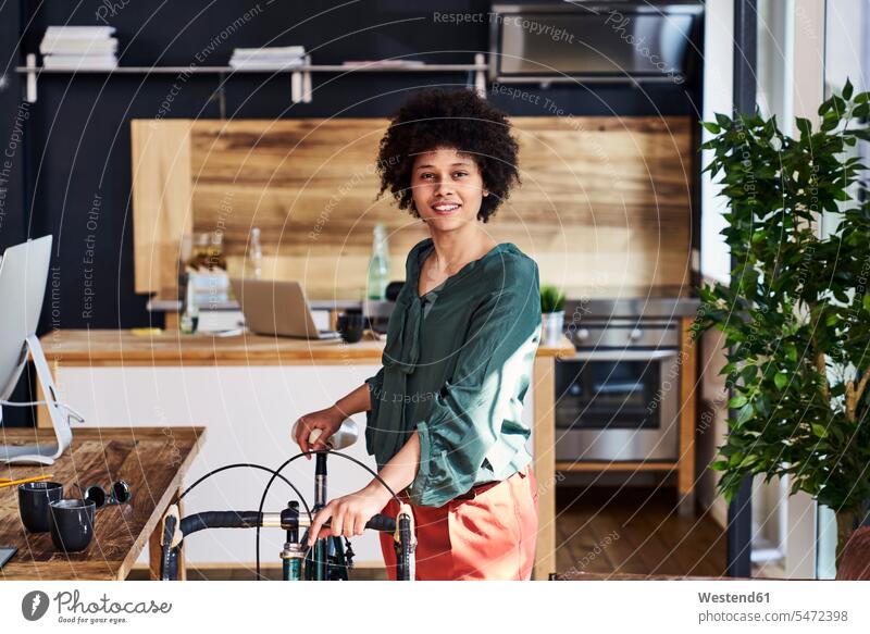 Portrait of smiling young woman with bicycle in modern office bikes bicycles contemporary portrait portraits offices office room office rooms smile females
