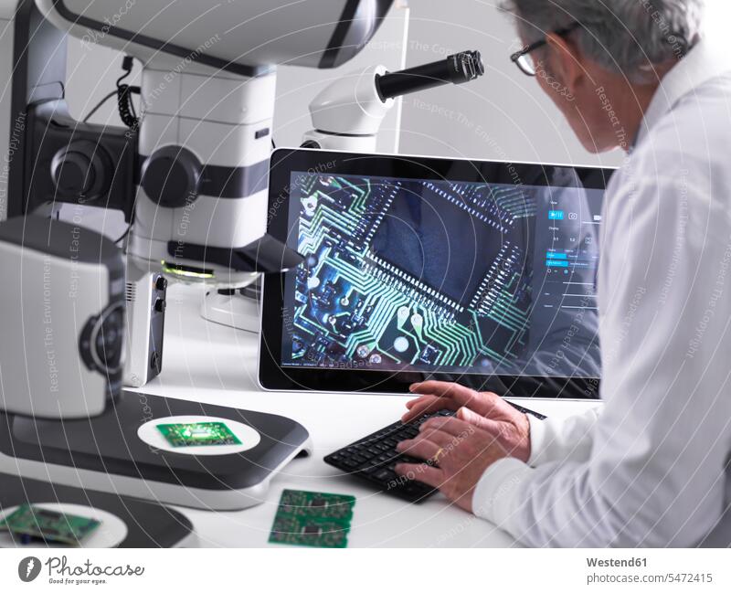 Engineer using a 3d stereo microscope for quality control in the manufacturing of circuit boards for the electronics industry scrutiny scrutinizing technician