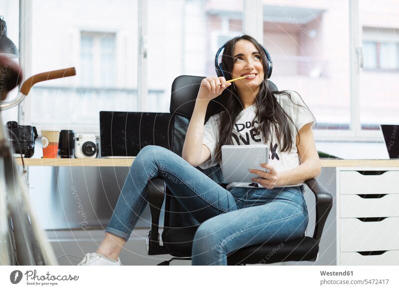 Casual young woman with notepad and headphones in coworking space pads Note Pad notepads Note Pads headset females women office offices office room office rooms