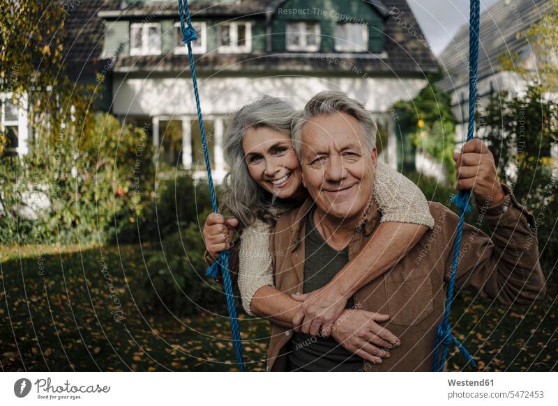 Portrait of a happy woman embracing senior man on a swing in garden human human being human beings humans person persons caucasian appearance