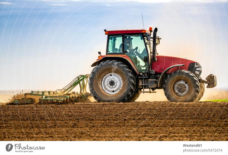 Farmer in tractor plowing field in spring agriculturist agriculturists farmers motor vehicles road vehicle road vehicles tractors drive seasons spring season