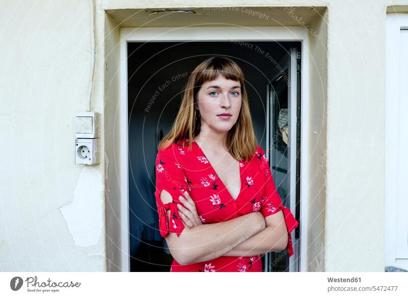 Portrait of serious young woman with arms crossed standing in front of opened balcony door human human being human beings humans person persons