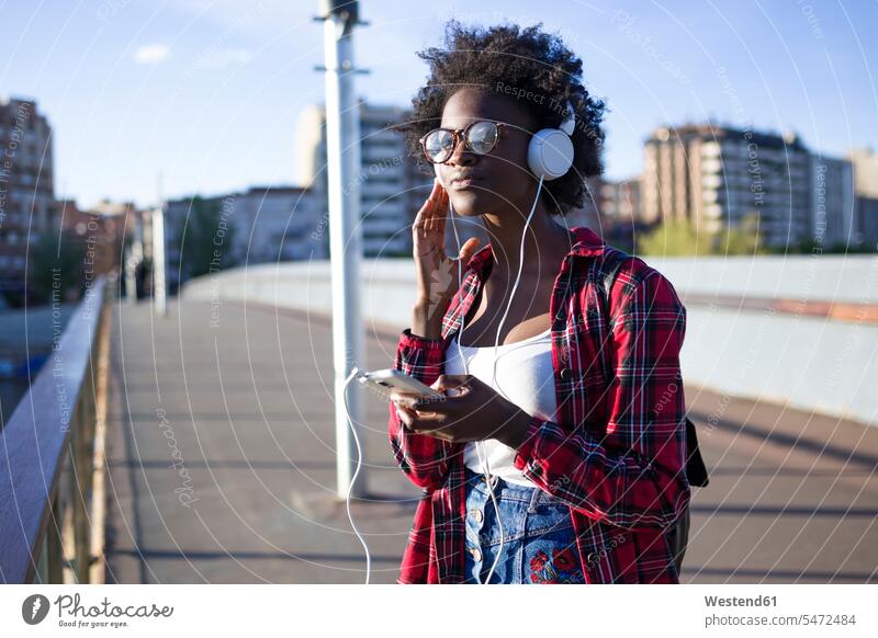 Portrait of young woman on a bridge listening music with headphones headset females women portrait portraits hearing bridges Adults grown-ups grownups adult