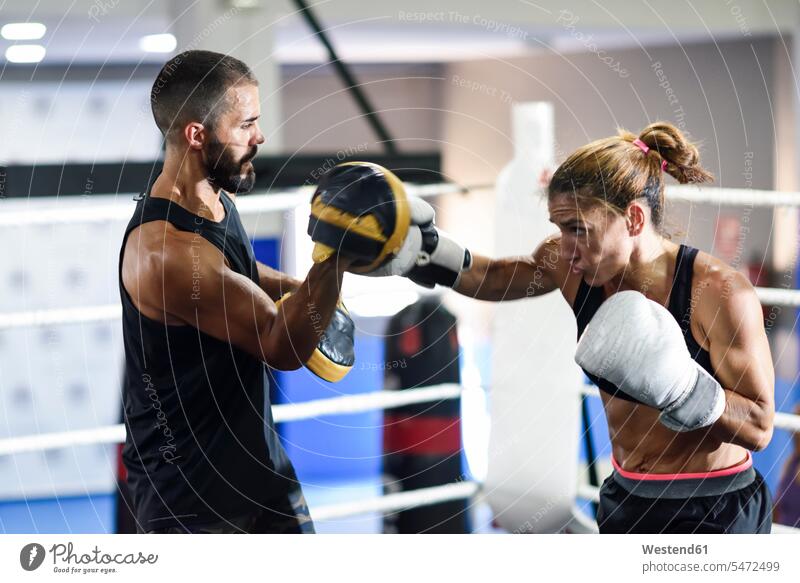 Female boxer sparring with her coach in gym coaches trainer exercise practising training learn exercising practice practise sports fit free time leisure time