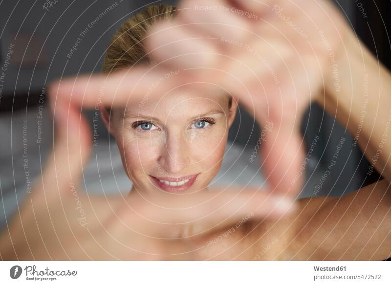 Portrait of smiling beautiful woman making a finger frame models heads faces human face human faces blue eye blue-eyed images picture pictures photo photographs