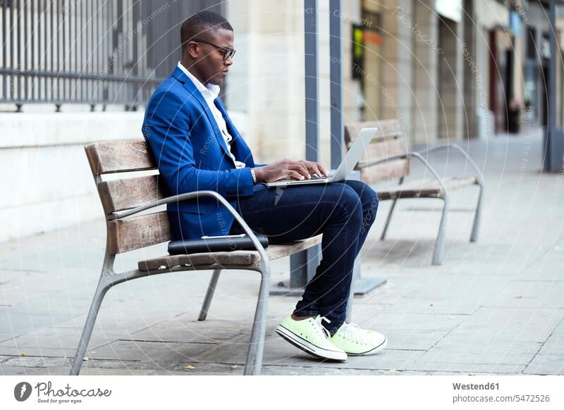 Young businessman wearing blue suit jacket sitting on bench and using laptop Occupation Work job jobs profession professional occupation business life