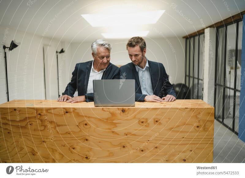 Two businesmen working at counter, looking at laptop, smiling generation Occupation Work job jobs profession professional occupation business life