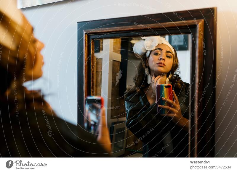 Female teenager taking selfie through smart phone looking at mirror color image colour image indoors indoor shot indoor shots interior interior view Interiors