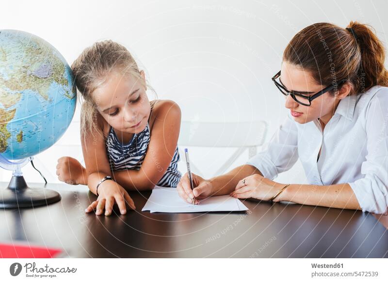 Teacher helping schoolgirl at desk writing on paper human human being human beings humans person persons caucasian appearance caucasian ethnicity european 2
