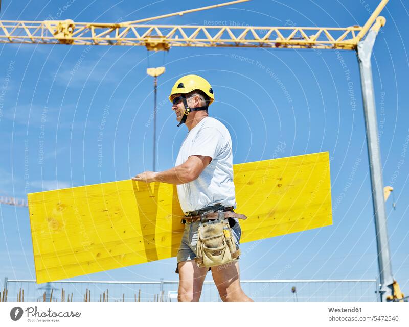 Construction worker carrying plywood construction site construction worker builders Building Site sites Building Sites construction sites craftsman trade