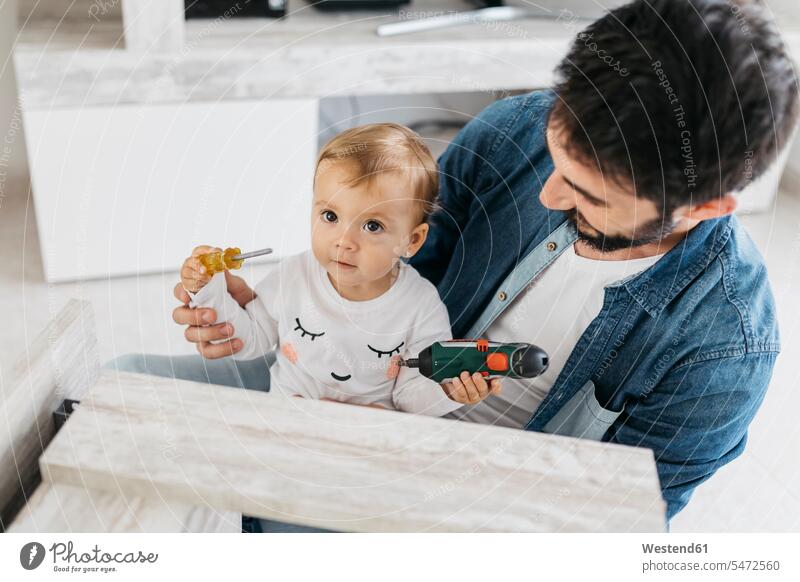 Father and daughter assembling a wooden table at home daughters father pa fathers daddy dads papa DIY Doityourself Do it yourself Do-it-yourself wood table