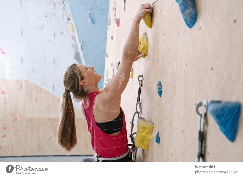 Happy woman climbing on the wall in climbing gym (value=0) human human being human beings humans person persons caucasian appearance caucasian ethnicity