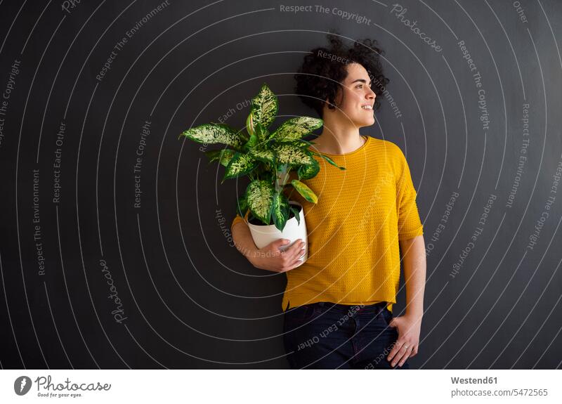 Portrait of young woman holding a house plant and looking sideways jumper sweater Sweaters smile delight enjoyment Pleasant pleasure happy Contented Emotion