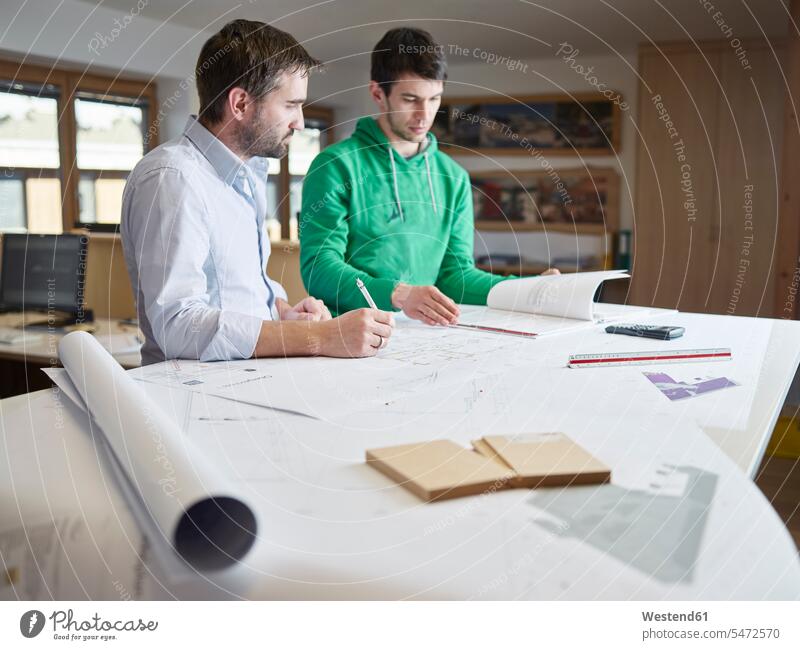 Architects working on construction drawing Cooperation working together collaboration Cooperating Cooperate Co-Operation Collaborating collaborate strategy