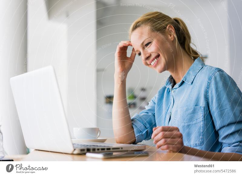 Blond woman sitting in coffee shop, using laptop computers Laptop Computer Laptop Computers laptops notebook At Work work smile Seated delight enjoyment