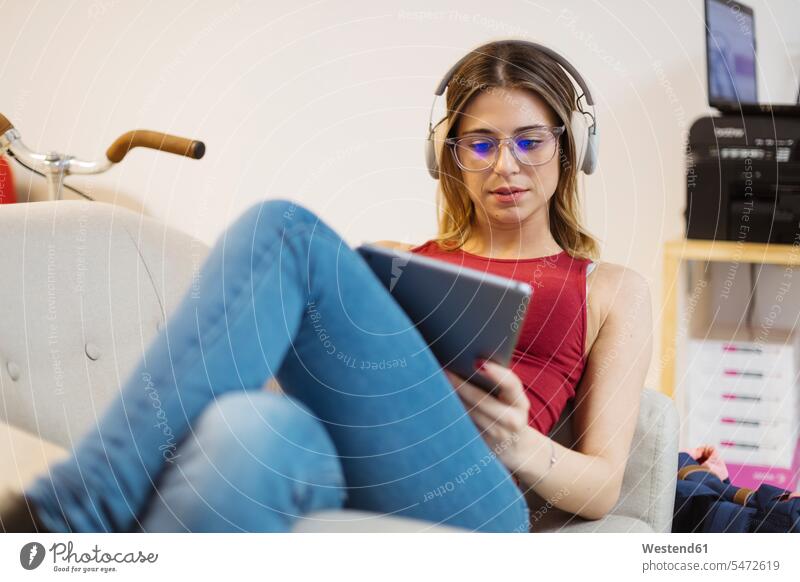 Casual young woman with headphones using tablet in coworking space office offices office room office rooms headset females women digitizer Tablet Computer