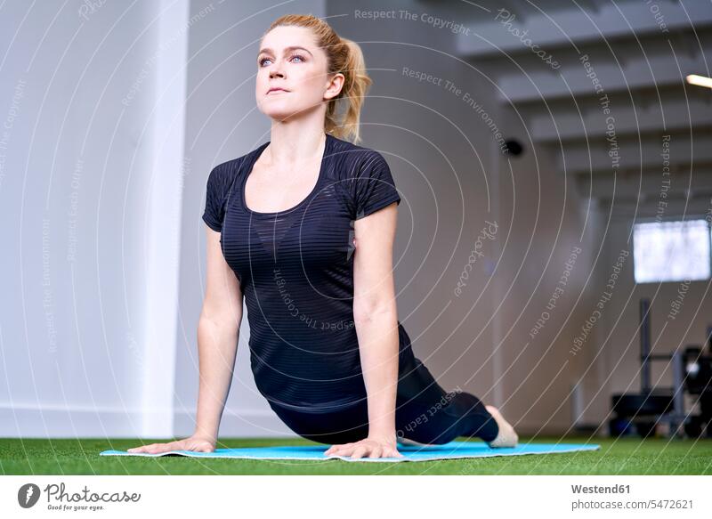 Woman doing yoga exercise in studio exercising training practising exercises studios woman females women mindfulness aware awareness self-care