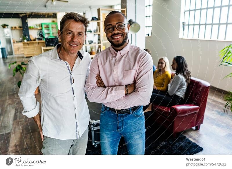 Portrait of two smiling businessmen with coworkers in background in loft office smile portrait portraits lofts Businessman Business man Businessmen Business men