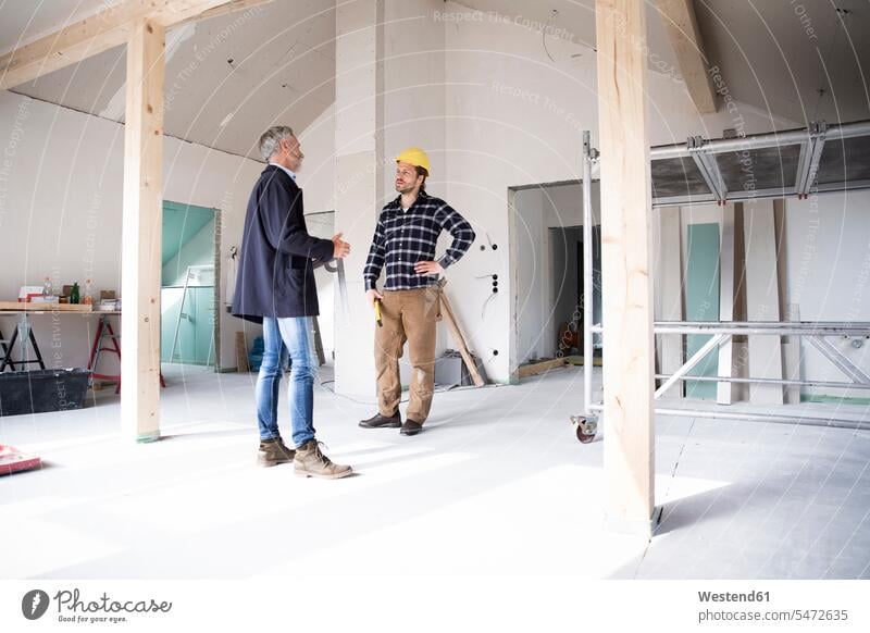 Architect and construction worker discussing while standing in renovating house color image colour image Germany Architecture construction site Building Site
