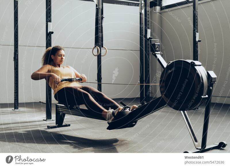 Young woman exercising in gym with rowing machine human human being human beings humans person persons Mixed Race mixed race ethnicity mixed-race Person 1