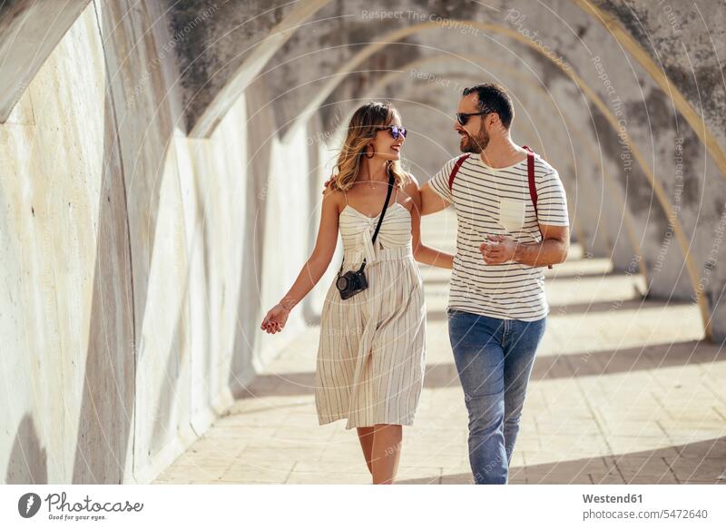 Spain, Andalusia, Malaga, happy tourist couple walking under an archway in the city town cities towns tourists happiness going twosomes partnership couples