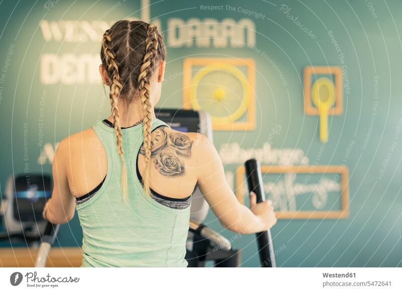 Rear view of young woman exercising on step machine in fitness gym exercise practising train training practice practise sports free time leisure time