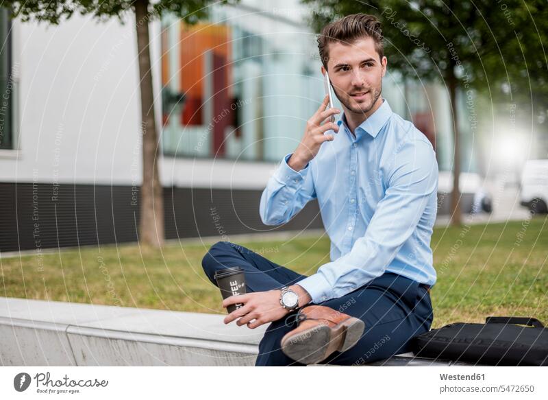 Smiling businessman sitting outdoors with cell phone and takeaway coffee Seated Coffee Businessman Business man Businessmen Business men smiling smile Drink