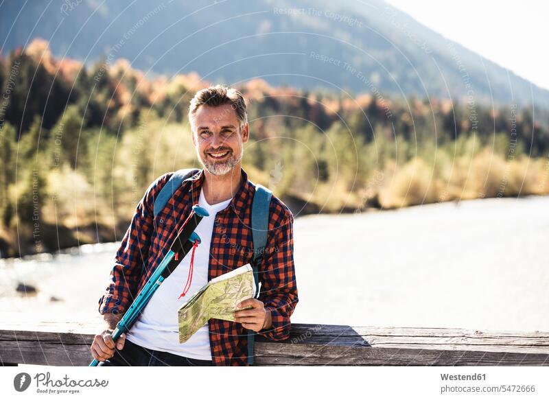 Austria, Alps, smiling man on a hiking trip with map on a bridge caucasian caucasian appearance caucasian ethnicity european White - Caucasian mature men