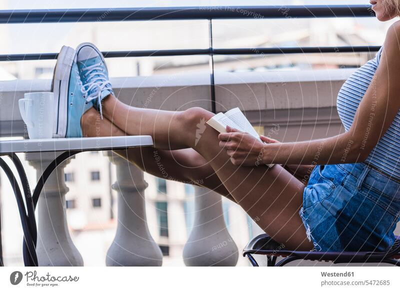 Blond woman sitting on balcony, reading book books Seated balconies females women Adults grown-ups grownups adult people persons human being humans human beings