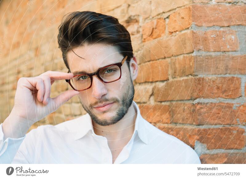 Portrait of a man wearing glasses at brick wall men males brick walls specs Eye Glasses spectacles Eyeglasses portrait portraits Adults grown-ups grownups adult