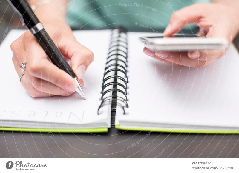 Woman writing notes in diary, holding smartphone date appointment Smartphone iPhone Smartphones organisation organised organization organized ballpen ball-pens