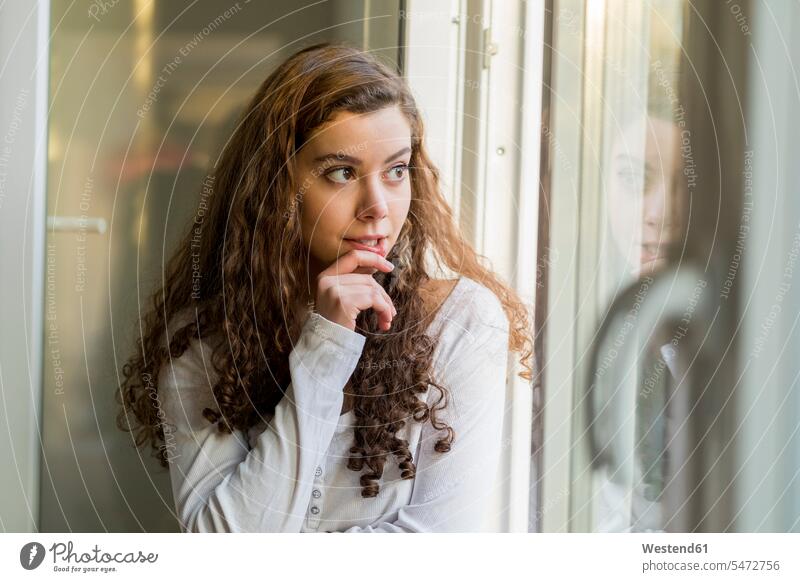 Teenage girl looking out of window, daydreaming Looking Through Window Looking Through A Window looking through glass Teenage Girls female teenagers portrait
