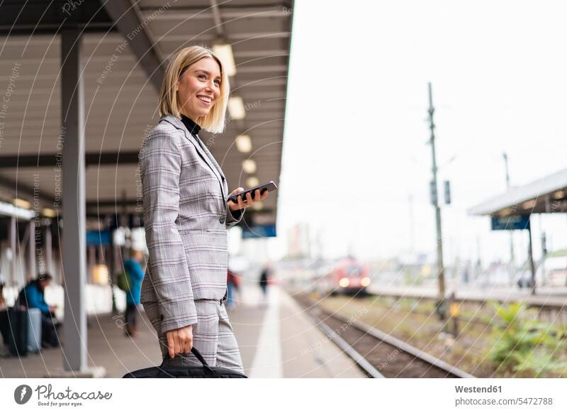Smiling young businesswoman with mobile phone at the train station business life business world business person businesspeople business woman business women