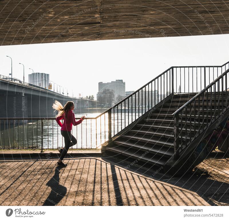 Young woman running towards stairs at a river River Rivers females women Jogging stairway water waters body of water Adults grown-ups grownups adult people