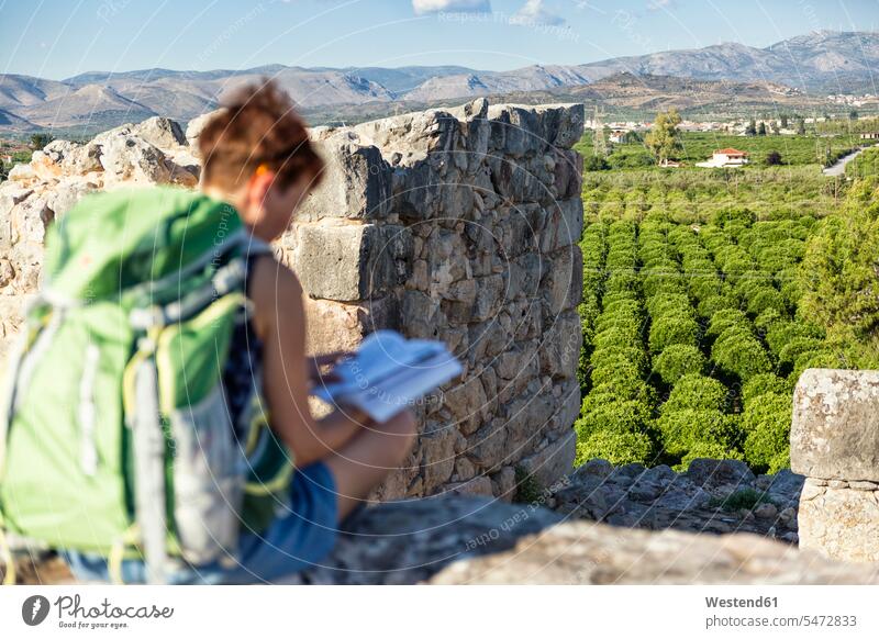 Greece, Peloponnese, Argolis, Tiryns, archaeological site, female tourist reading guide book books informing guidebook tour guide tourist guide travel guide