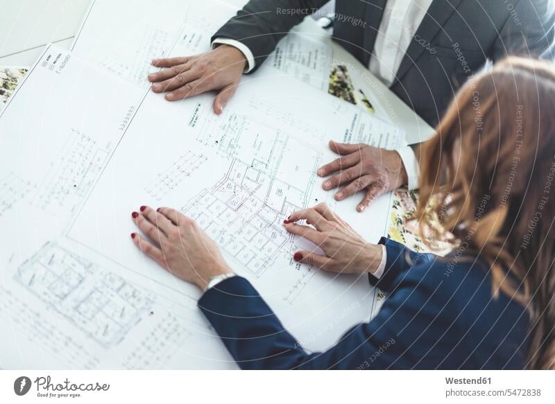 Close-up of businesswoman and businessman working on plan on desk in office human human being human beings humans person persons caucasian appearance
