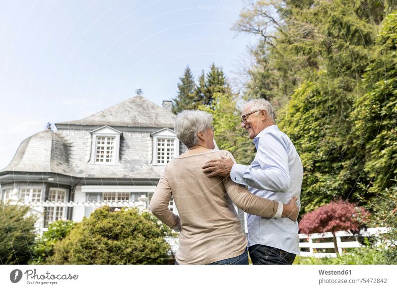 Rear view of senior couple standing in garden of their home smile delight enjoyment Pleasant pleasure happy Contented Emotion pleased at home Retired free time