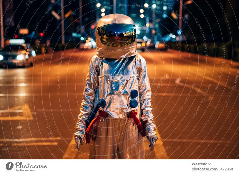 Spaceman standing on a street in the city at night spaceman spacemen astronaut astronauts road streets roads town cities towns by night nite night photography