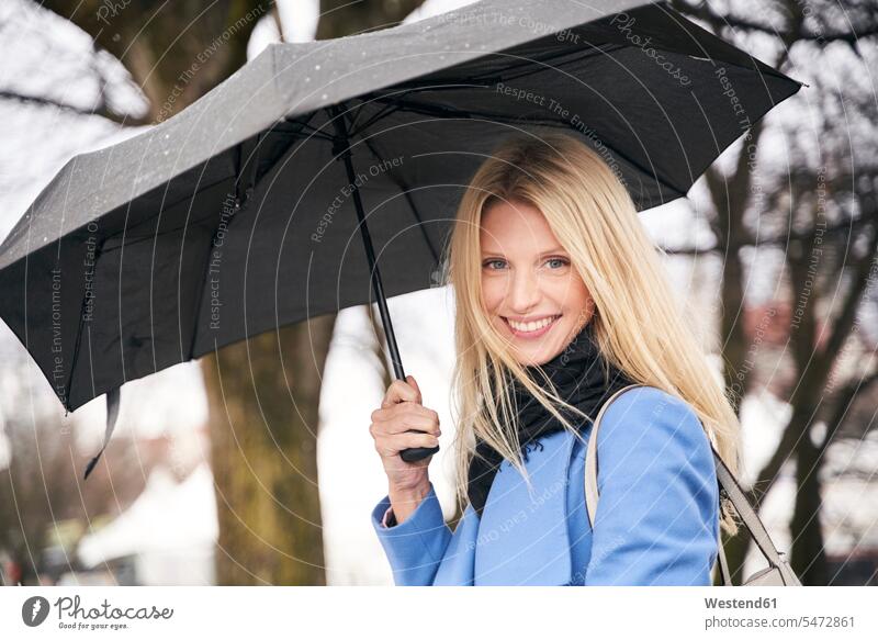 Portrait of smiling blond woman holding umbrella outdoors scarfs scarves Brolly umbrellas smile delight enjoyment Pleasant pleasure happy Contented Emotion