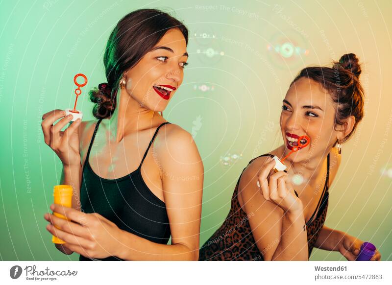 Portrait of two friends having fun with soap bubbles mate female friend celebrate partying fly play seasons summer time summertime summery Ardor Ardour