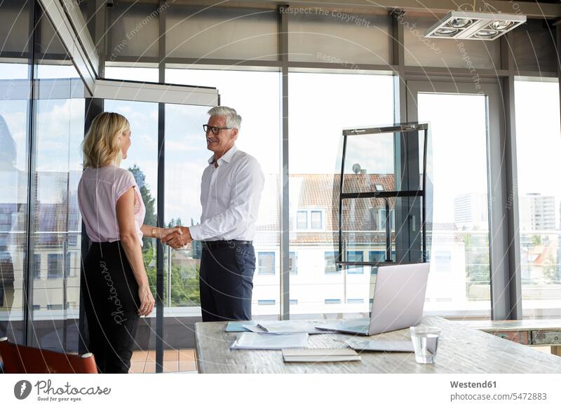 Businessman and woman shaking hands in office discussing discussion greeting Meeting Meetings Business Meeting Business man Businessmen Business men