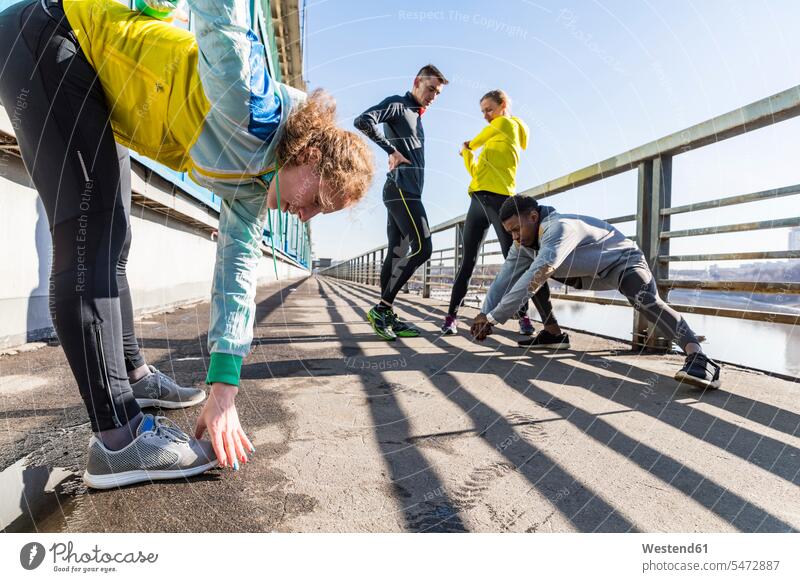 Friends doing stretching exercise on bridge in the city exercises town cities towns friends mate outdoors outdoor shots location shot location shots friendship