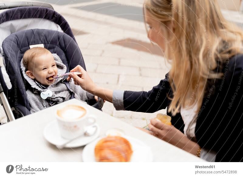 Mother feeding laughing baby boy in stroller eating spoon spoons Pastry Pastries Fun having fun funny cute twee Cutie pavement cafe outdoor cafes pushchair