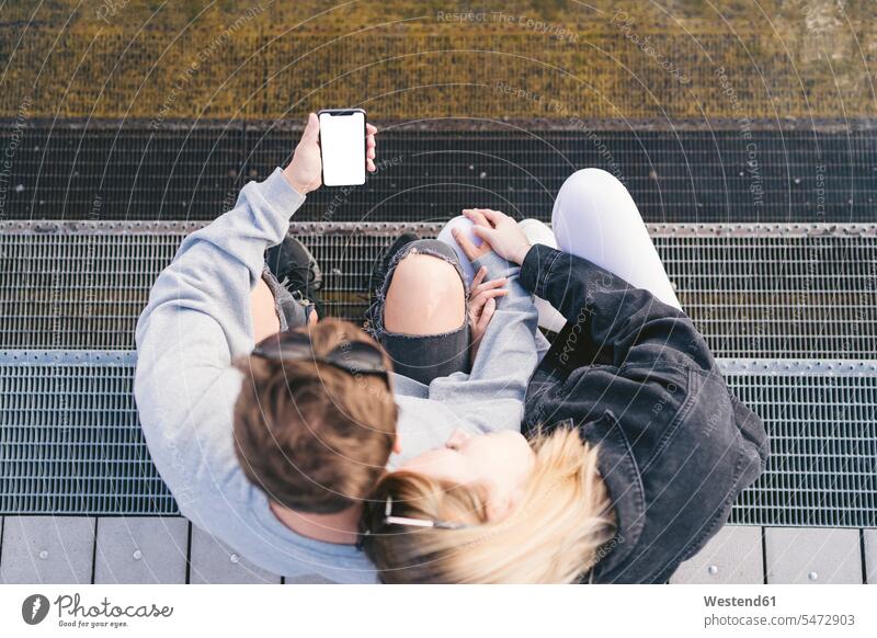 Young couple sitting stairs looking at smartphone telecommunication phones telephone telephones cell phone cell phones Cellphone mobile mobile phones mobiles