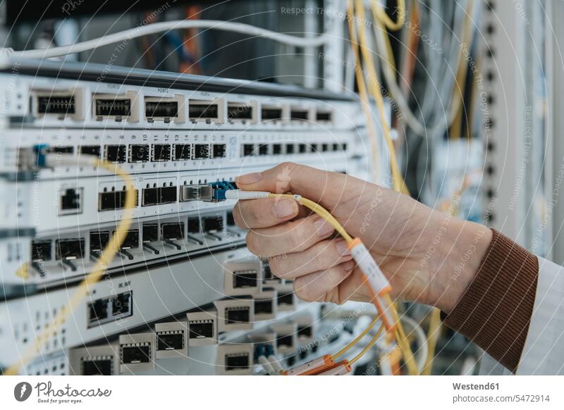 Close-up of woman plugging fiber optic cable in equipment at data center color image colour image indoors indoor shot indoor shots interior interior view