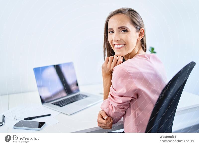Cheerful young businesswoman smiling at camera while working in office Occupation Work job jobs profession professional occupation business life business world
